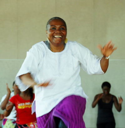 Naomi Diouf demonstrating, with irrepressible energy, moves across the floor for her students to imitate.